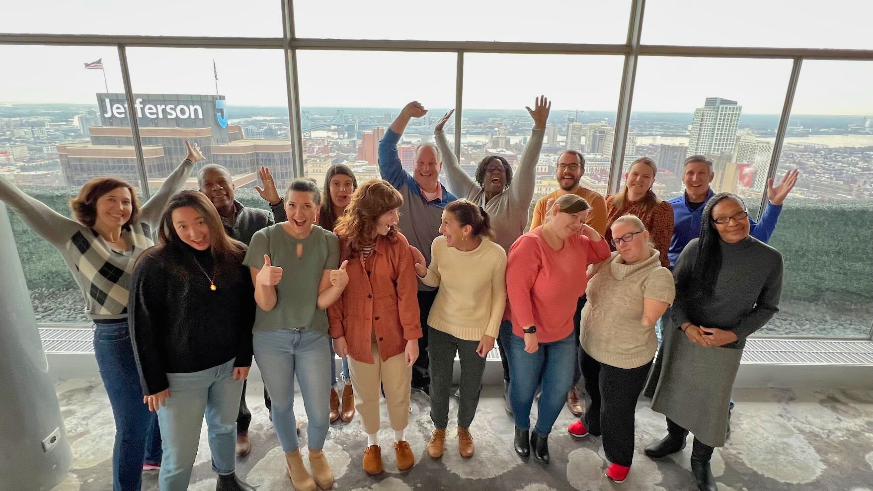 The CM Event Solutions team standing in front of a large glass window in a high building