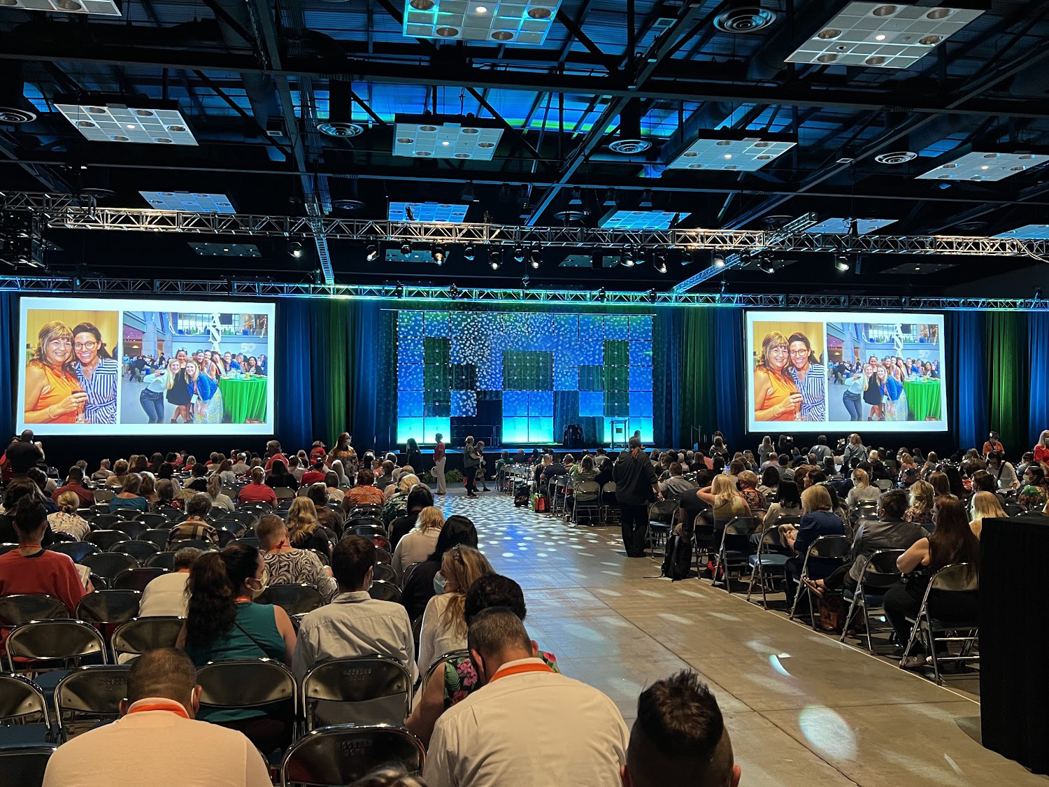 A crowd of people sitting at a conference waiting for the keynote speaker to begin.